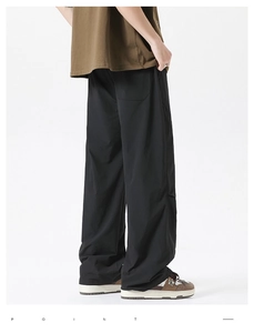 Detail view of black loose wide-leg casual pants showing draped fabric and back pocket design
