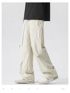 Detail of off-white wide-leg pleated trousers with adjustable drawstring and tactical cut