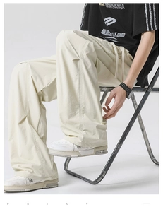 Macro view showing the pleated texture and drawstring waist of cream wide-leg pants