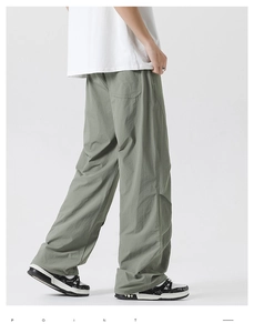 Detailed view of sage green men's straight leg trousers featuring pleated nylon fabric texture