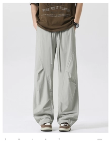 Detail view of men's olive straight-leg pants with pleated seams and drawstring waist