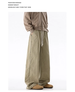 Detail of men's oversize cotton trousers with elastic drawstring waist in khaki