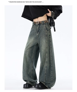 Detail of baggy washed blue jeans with a distressed finish and leopard print belt