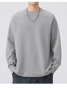 Detail of grey crewneck sweatshirt featuring raglan sleeves and smooth cotton texture