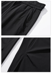 Detailed macro view of black quick-dry pants with elastic waistband and pleated texture