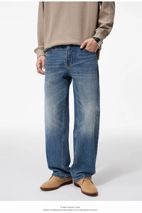 Detail view of men's blue straight-leg jeans with vintage washed texture and faded knees