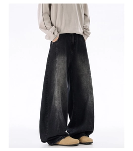 Detail of wide-leg distressed denim jeans showing washed gradient texture and draping style