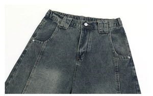 Detail of vintage washed denim jeans featuring elastic waist and metallic button closure