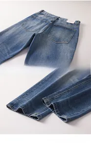 Detail view of washed blue denim texture on rear pockets and hem of straight leg jeans