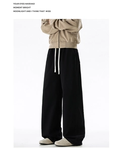 Detail view of men's black oversize trousers with thick white drawstring waist cord