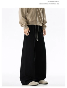 Detail of black cotton wide-leg joggers featuring a white drawstring and oversized fit