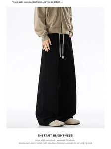 Detail of oversized black cotton trousers featuring a contrast white drawstring waist