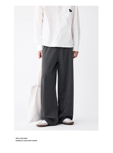 Full view of wide leg pinstripe trousers with white shirt and sneakers in minimalist style