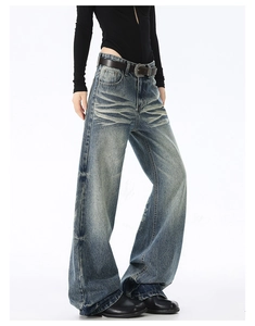 Dettaglio dei jeans larghi lavaggio vintage con baffi di gatto e vestibilità ampia
