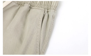 Detail view of khaki cotton trousers featuring elastic waistband with drawstring and pockets