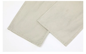 Detailed close-up of light khaki twill cotton fabric and precise stitching on the pant leg hem