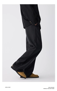 Detail of black wide-leg trousers with subtle striped texture and elegant drape effect