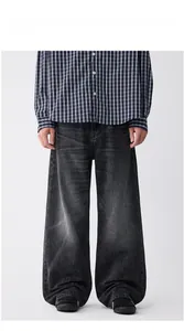 Modèle homme portant un jean délavé gris foncé ample et une chemise à carreaux bleue