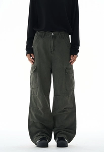 Detail of baggy olive green cargo pants showing reinforced knee stitching and large side pockets