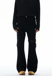 Detail of black utility cargo pants featuring metal buckle straps and side flap pockets