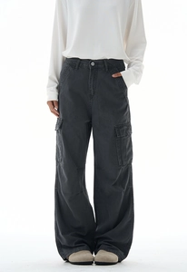 Detail of dark grey baggy cargo pants featuring side flap pockets and stitching