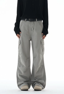 Detail of grey wide-leg cargo pants featuring large flap pockets and layered hem cuffs