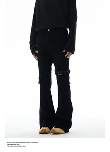 Detail view of black cargo pants featuring metallic eyelet straps and utility buckle design