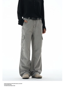 Detail of cargo pants showing oversized utility pockets and knee stitching on grey fabric
