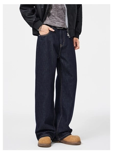 Dettaglio di jeans blu scuro dal taglio ampio con cuciture a contrasto e texture premium