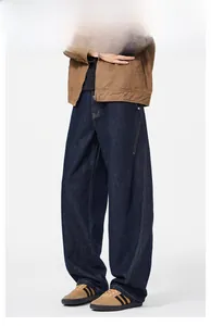Detail of wide-leg dark blue denim jeans with orange contrast stitching and relaxed fit