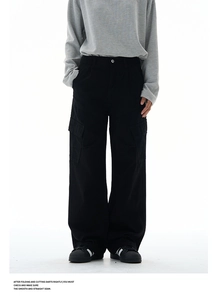 Detail shot of large cargo pockets and durable fabric on black wide-leg trousers
