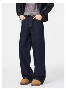 Dettaglio dei jeans in denim blu scuro con cuciture gialle e cintura in pelle nera