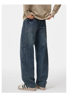 Dettaglio del lavaggio vintage blu profondo e della tasca grande sui jeans ampi da uomo