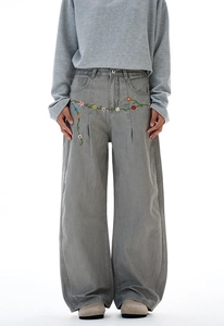 Detail of colorful floral embroidery on high-waisted gray-green wide-leg denim pants