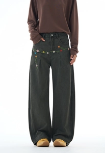Close-up of colorful daisy embroidery details on dark grey wide-leg street jeans
