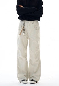 Dettaglio dei pantaloni cargo beige con pieghe sulle ginocchia e catena in vita
