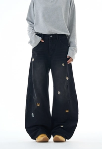 Detail einer lockeren schwarzen Jeanshose mit süßer Bärenstickerei und Metallknopf