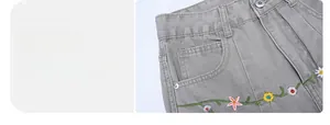 Detail of grey streetwear jeans featuring colorful floral embroidery and high-quality stitching