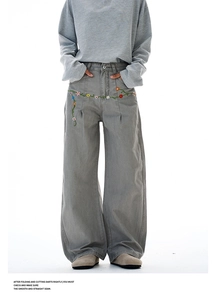 Detail of floral vine embroidery on vintage gray wide-leg trousers with pleated design
