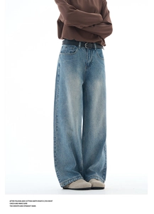 Detail of high waist light blue washed denim jeans with a black leather belt
