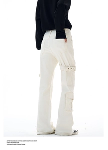Detailed macro view of white cargo pants featuring metallic buckles and side pocket design