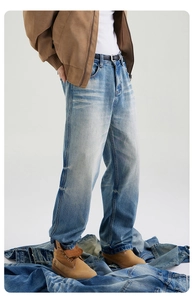 Detail of light blue washed denim jeans featuring vintage cat whisker fading and a straight cut