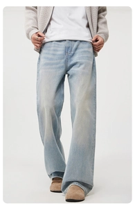 Close-up detail of light blue wash denim texture and whiskering on men's relaxed jeans