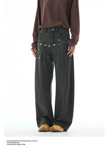 Detail of vintage dark green wide-leg trousers with colorful floral embroidery on waist