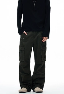 Detail of dark green cargo pants with rivet flap pockets and straight loose fit