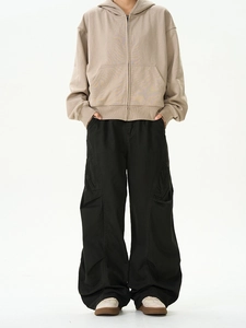 Detailansicht von khakifarbenem Kapuzenpullover und schwarzer Cargo-Hose im Oversize-Stil