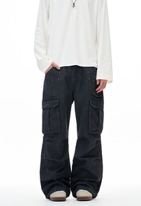 Detail view of black multi-pocket cargo pants with silver rivets and washed texture