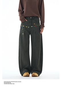 Detailed view of colorful floral embroidery and heavy denim fabric on wide-leg jeans