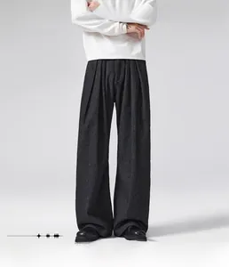 Detail of loose straight fit black pinstripe trousers with elegant pleated waist design