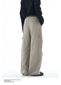 Detail view of khaki multi-pocket cargo pants showing wide-leg cut and twill texture